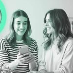 Duas sorridentes jovens influencers segurando um celular em frente a um anel de luz - representando Influencer Digital